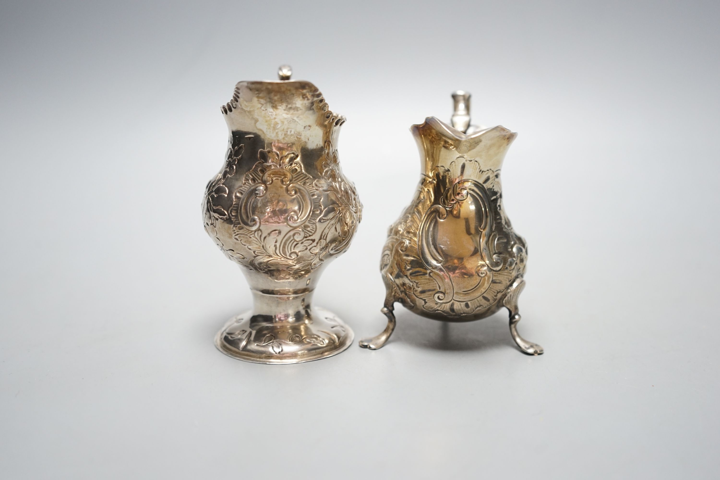 Two 18th century silver cream jugs, with later embossed decoration, London, 1753 & London, 1770, tallest 10.6cm, 174 grams.